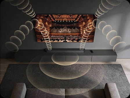 A Samsung TV and soundbar play a concert hall scene, with layered sound waves illustrating Q-Symphony synchronizing speakers for fuller audio.
